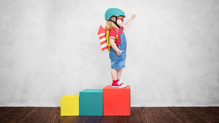 A child standing on a block with a jetpack