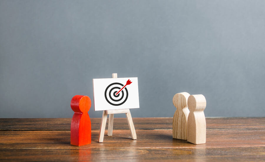 Toy figurines standing around a target with a red arrow in it