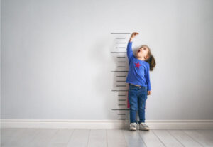 little girl looking at growth chart drawn on wall in awe